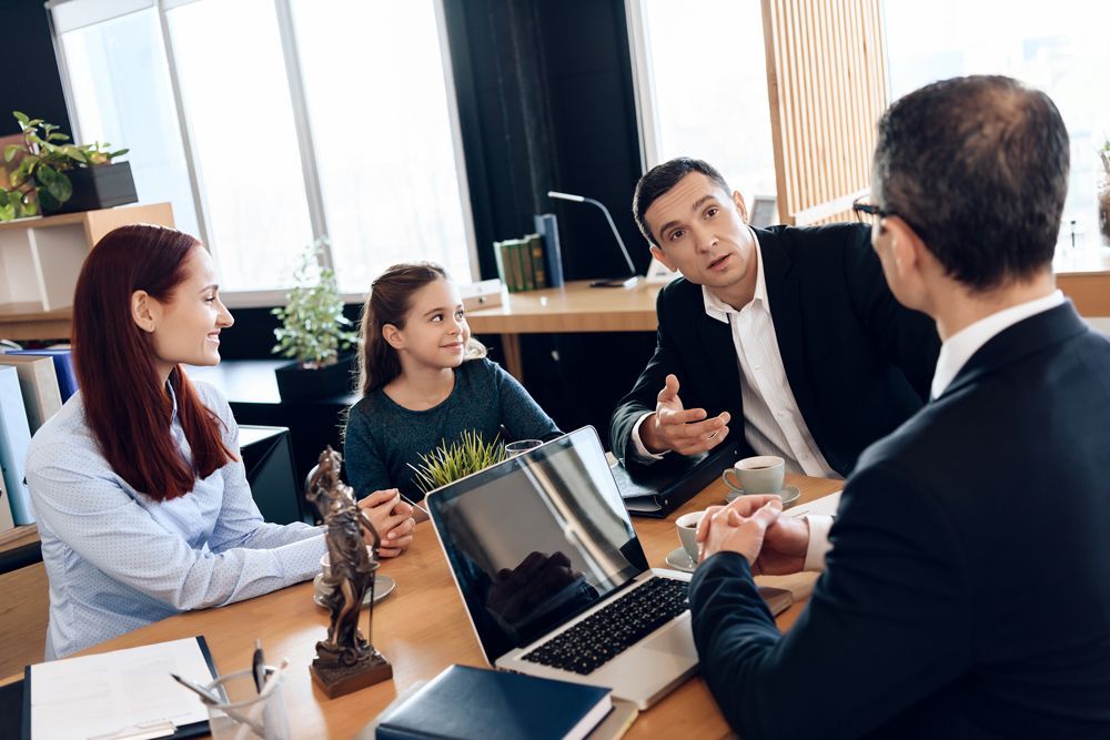 A family is sitting at a table talking to a lawyer.