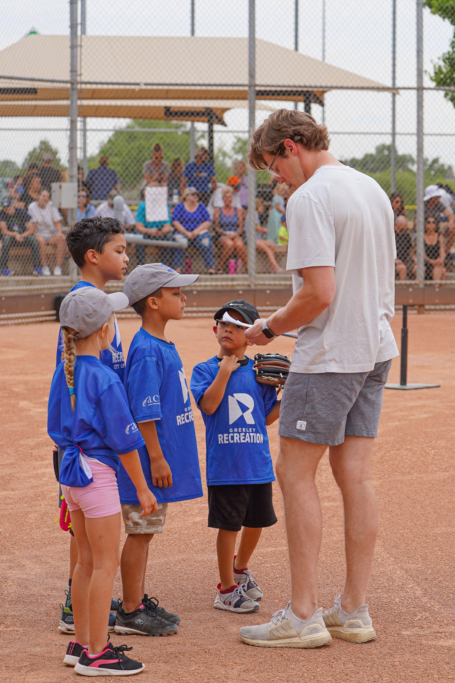 Coach talking to children in blue sports uniforms on a tennis court.