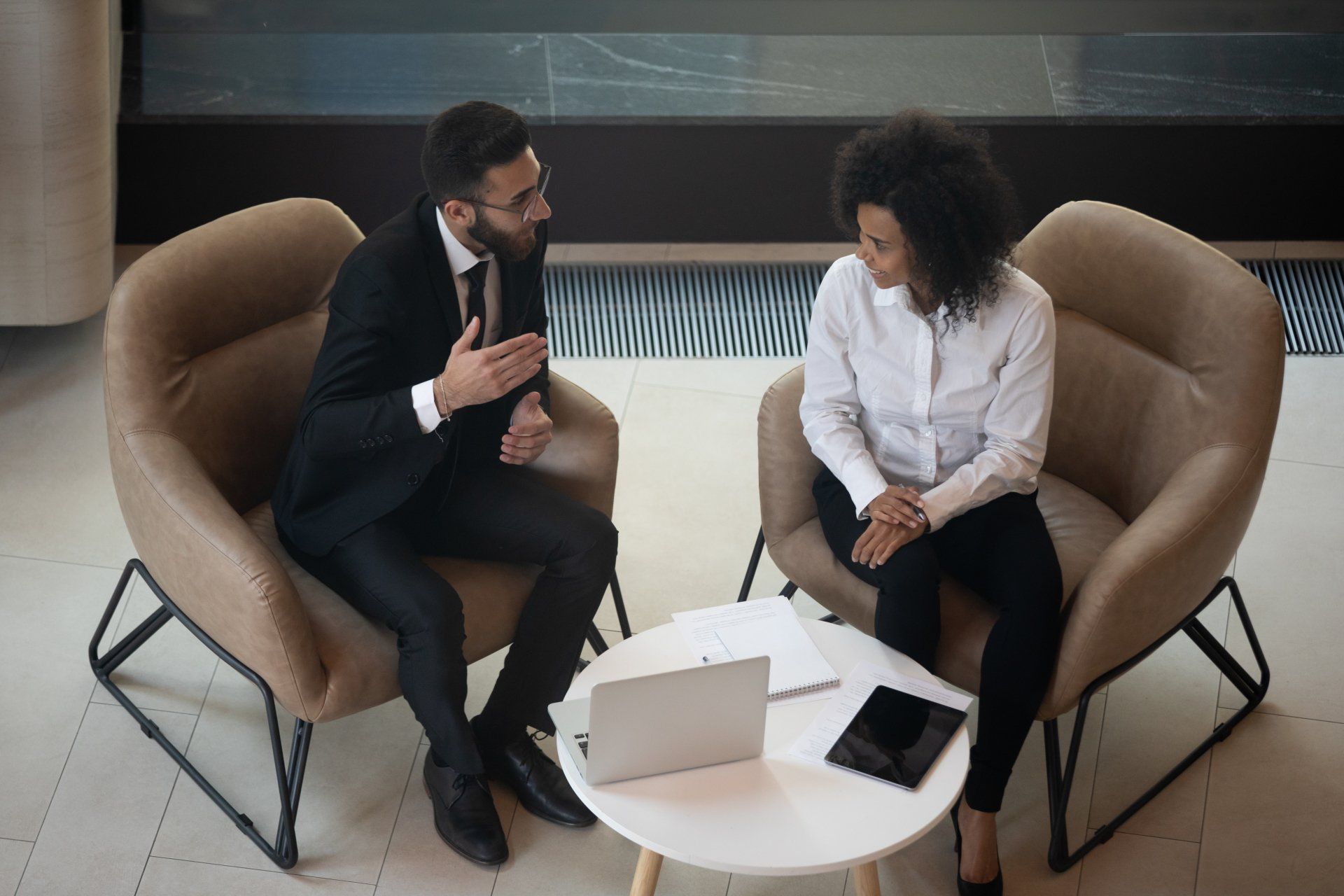 Business partners discussing project, sitting in armchairs top view