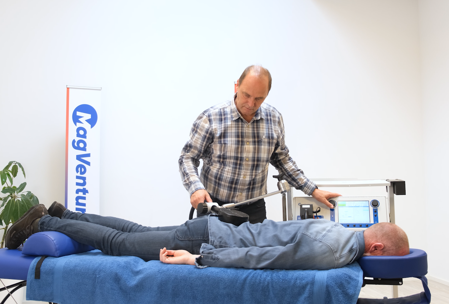 A man is standing next to a man laying on a table.