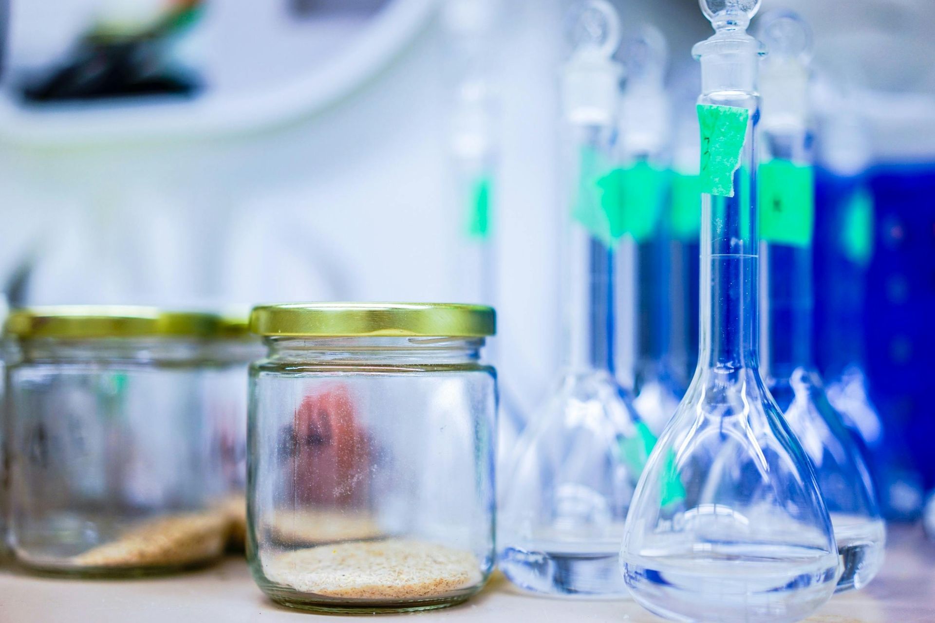 A row of beakers and jars on a table in a laboratory.