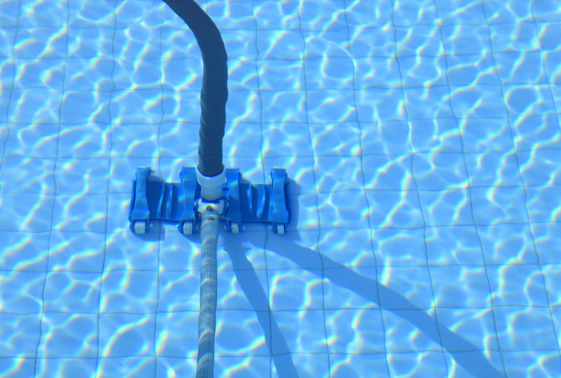 Blue pool vacuum cleaning a tiled pool bottom.