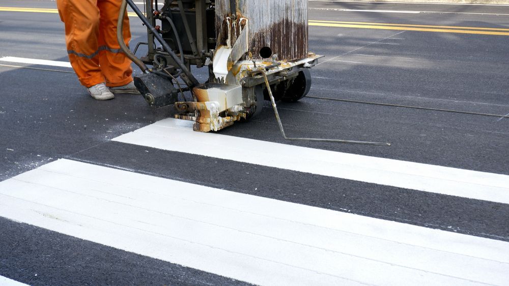 Person in Orange Suit Using a Road Marking Machine — ALI Civil Pty Ltd in South Nowra, NSW
