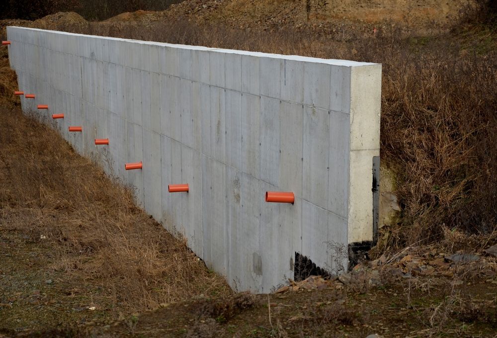 Concrete Retaining Wall With Orange Pipes, Situated in a Grassy Field — ALI Civil Pty Ltd in South Nowra, NSW