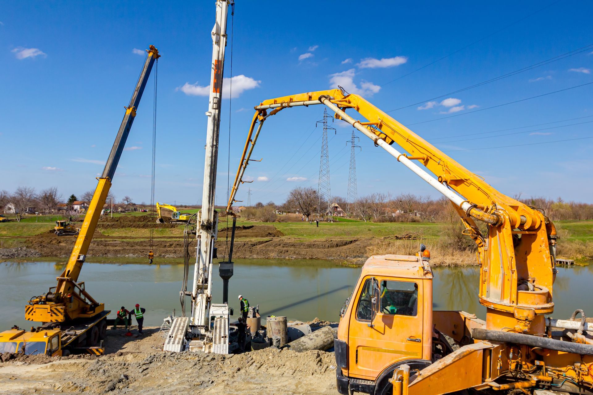 Construction Site With Crane, Drilling Machine, and Concrete Pump Near a River — ALI Civil Pty Ltd in Jervis Bay, NSW