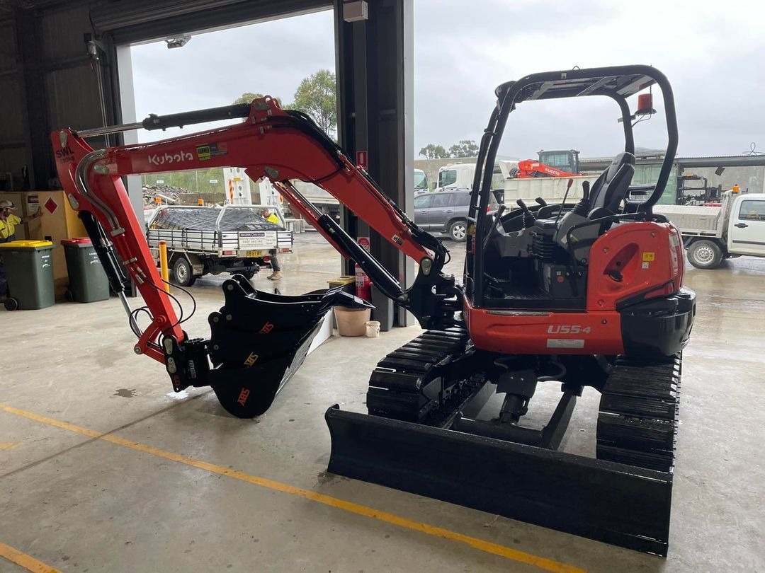 Red Kubota Mini Excavator With Black Bucket and Blade Indoors — ALI Civil Pty Ltd in Kiama, NSW