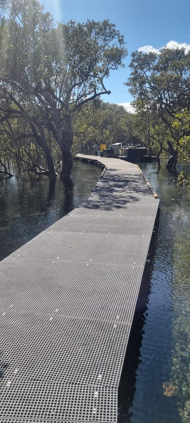 A Boardwalk Winds Through Water, Surrounded by Trees Under a Bright Blue Sky — ALI Civil Pty Ltd in Sussex Inlet, NSW