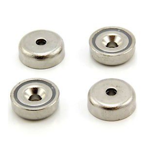 Four stainless steel magnets with holes in them on a white surface.