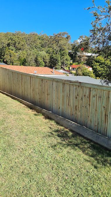 A Wooden Fence Is Sitting On Top Of A Lush Green Lawn — AAA Fencing & Supplies in Southport, QLD
