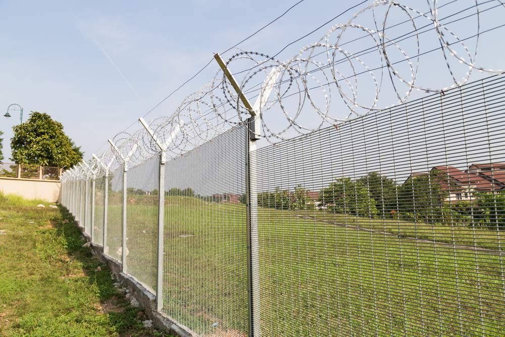 A Barbed Wire Fence Surrounds A Grassy Field — AAA Fencing & Supplies in Southport, QLD