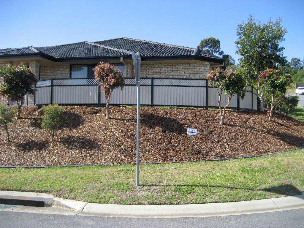 A House With A Fence And Trees In Front Of It — AAA Fencing & Supplies in Southport, QLD