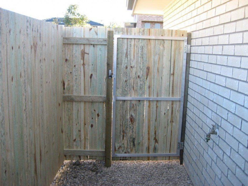 A Wooden Fence With A Metal Gate Is Next To A White Brick Wall — AAA Fencing & Supplies in Southport, QLD