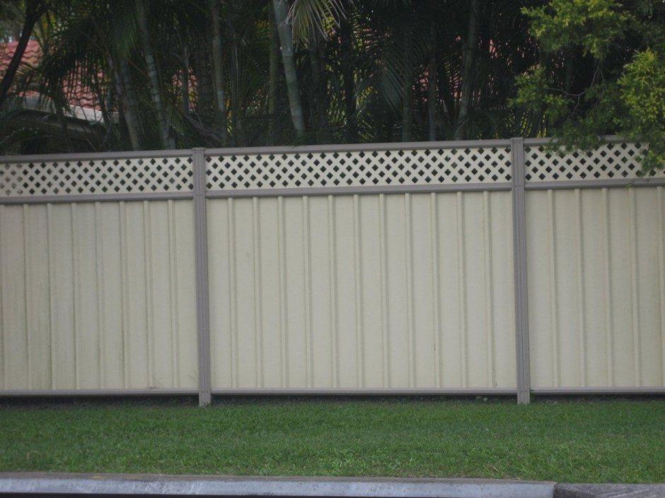A White Fence With A Lattice Top Is Surrounded By Grass And Trees — AAA Fencing & Supplies in Southport, QLD