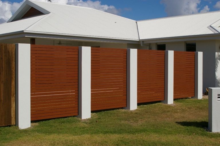 A White House With A Wooden Privacy Fence In Front Of It — AAA Fencing & Supplies in Southport, QLD