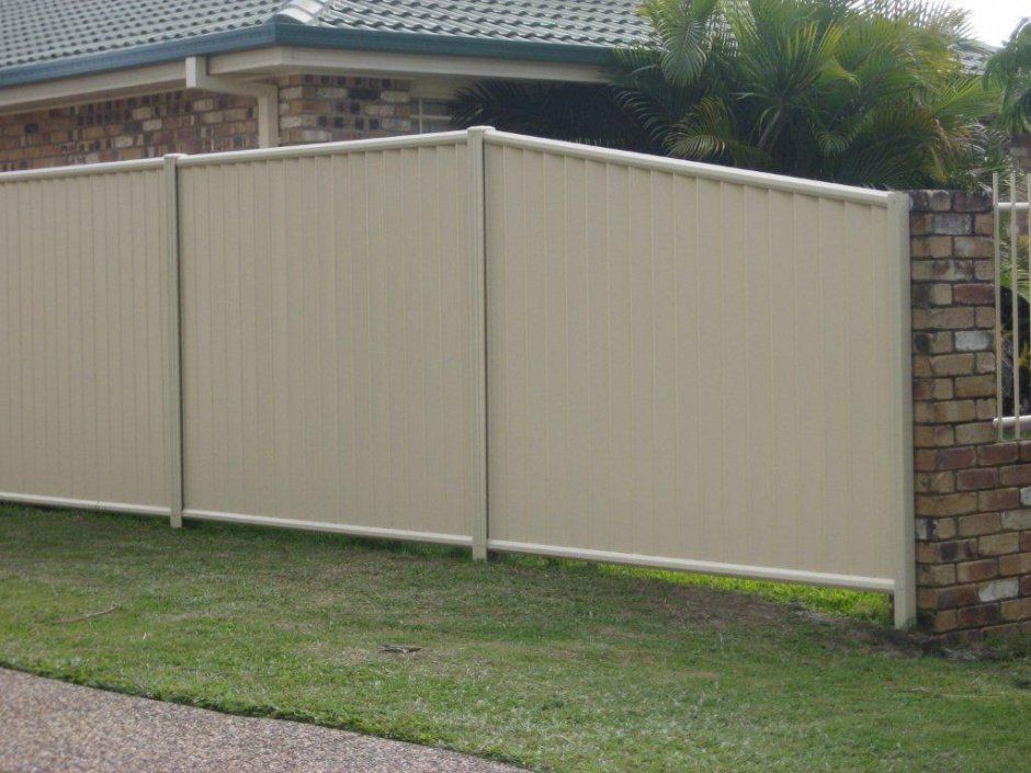 A White Fence Is Surrounding A Brick Wall House — AAA Fencing & Supplies in Southport, QLD