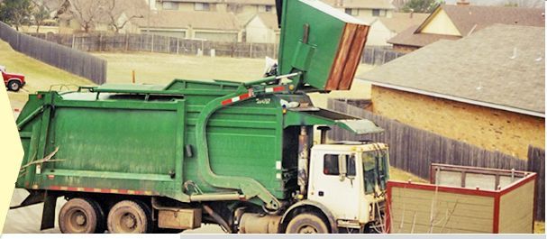 Green garbage truck, lifting container in a residential area.