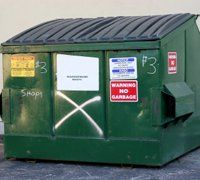 Green commercial dumpster with black lid; labeled with a 