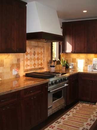 Modern kitchen with dark wood cabinets, tan tile backsplash, and stainless steel stove.