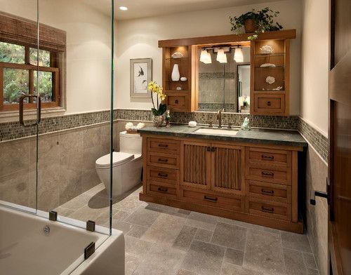 Spacious beige bathroom with a wood vanity, large mirror, tub shower, and stone tile floor