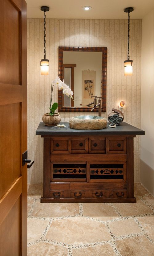 Warm beige bathroom with wooden vanity, stone sink, mirror, and hanging pendant lights.