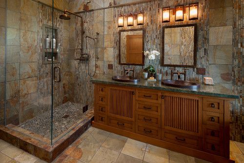 Luxurious bathroom with stone shower, double vanity, and warm wood cabinets and lights