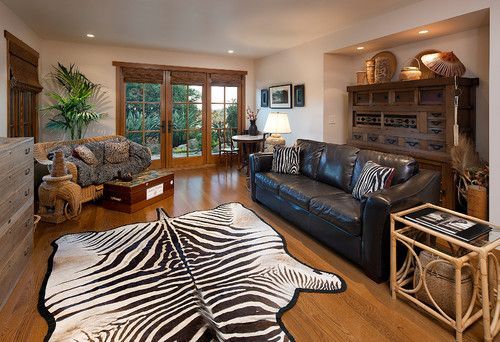 Cozy living room with leather sofa, zebra rug, wood furniture, and large windows to a patio