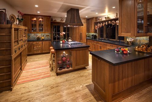Spacious gourmet kitchen with wood cabinets, black countertops, island, and warm recessed lighting.