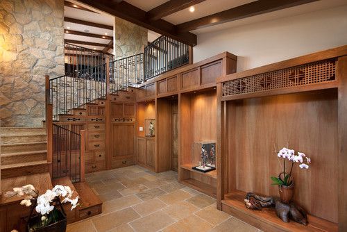 Warm wood-paneled entryway with stone stairs, railing, and orchid arrangement on a shelf