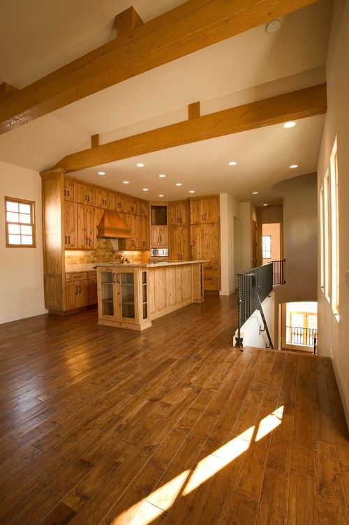 Bright open kitchen with wood floors, exposed beams, island, and sunlight streaming in