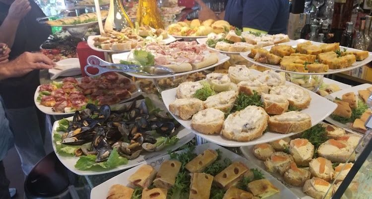 Piatti di antipasti al bar, tra cui cozze, panini e piccoli stuzzichini.