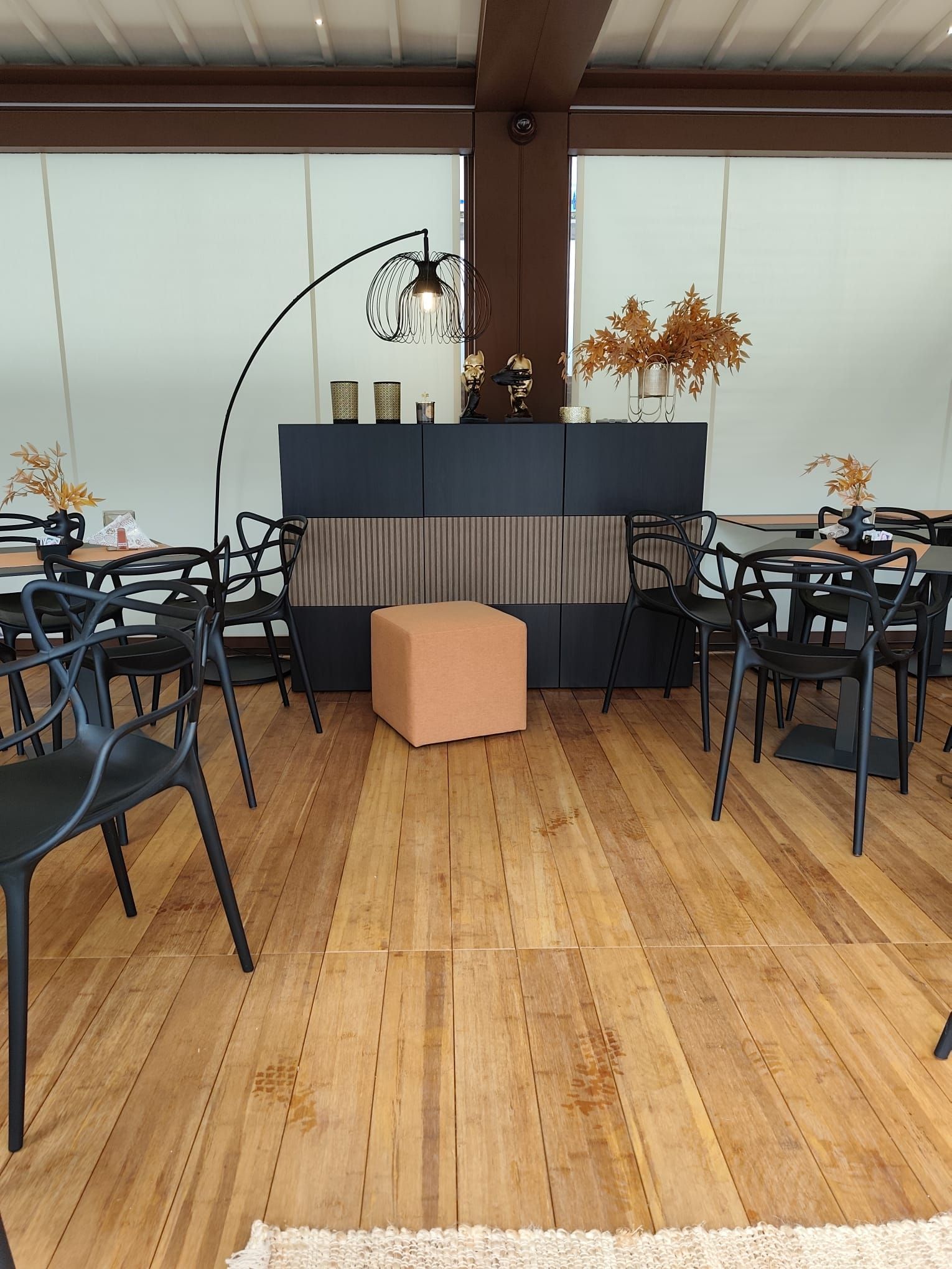 Interno con sedie e tavoli neri, pavimento in legno marrone e una panca incorporata marrone scuro.