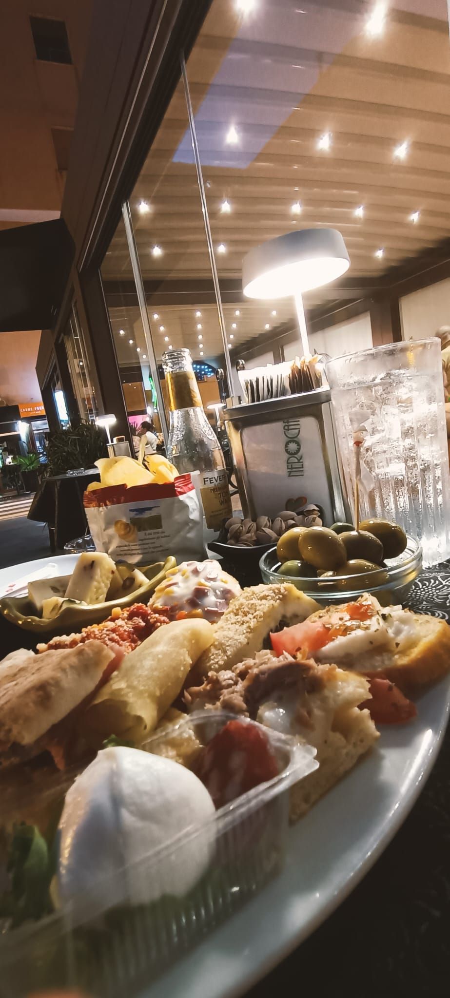 Un piatto di antipasti e salse su un tavolo in un ristorante scarsamente illuminato.