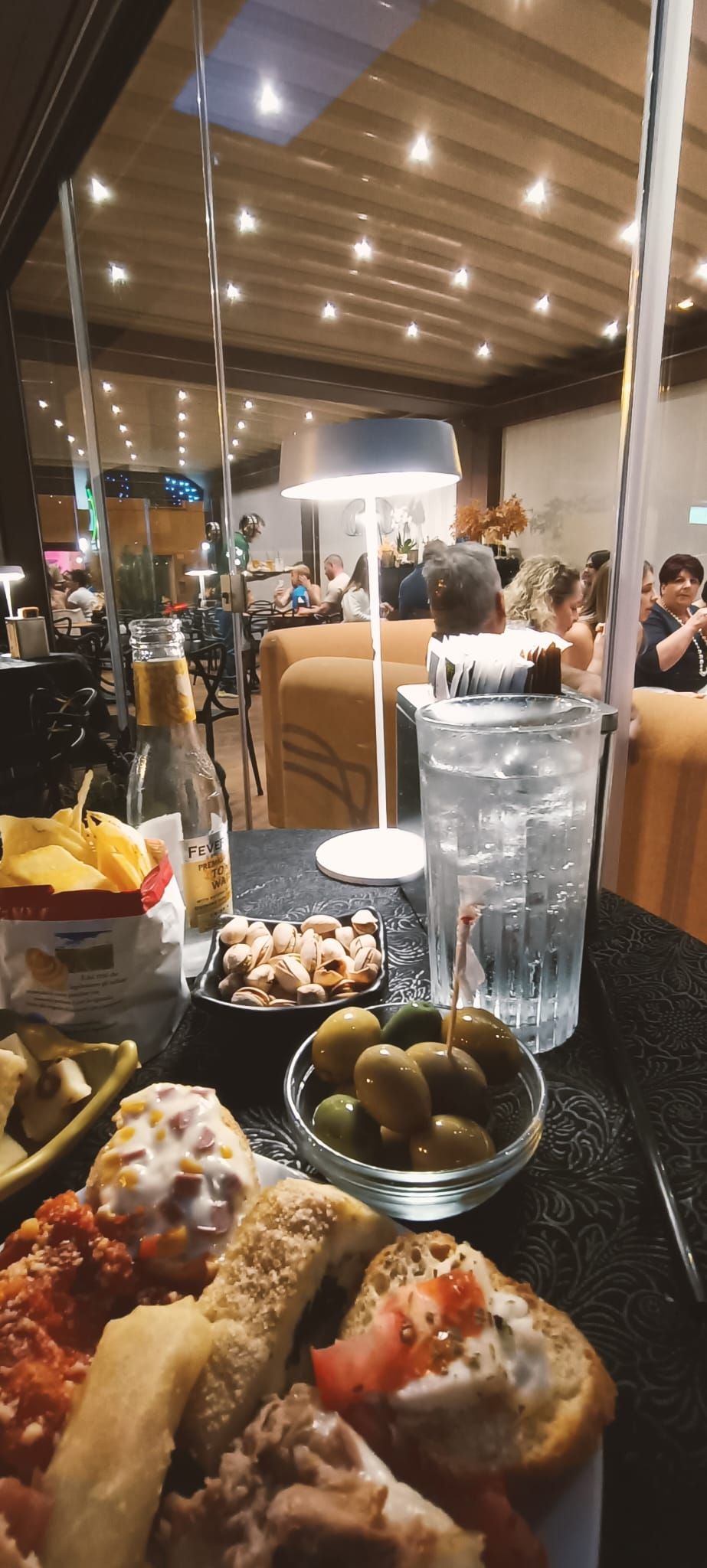 Antipasti e bevande al bar, sullo sfondo l'interno di un ristorante.