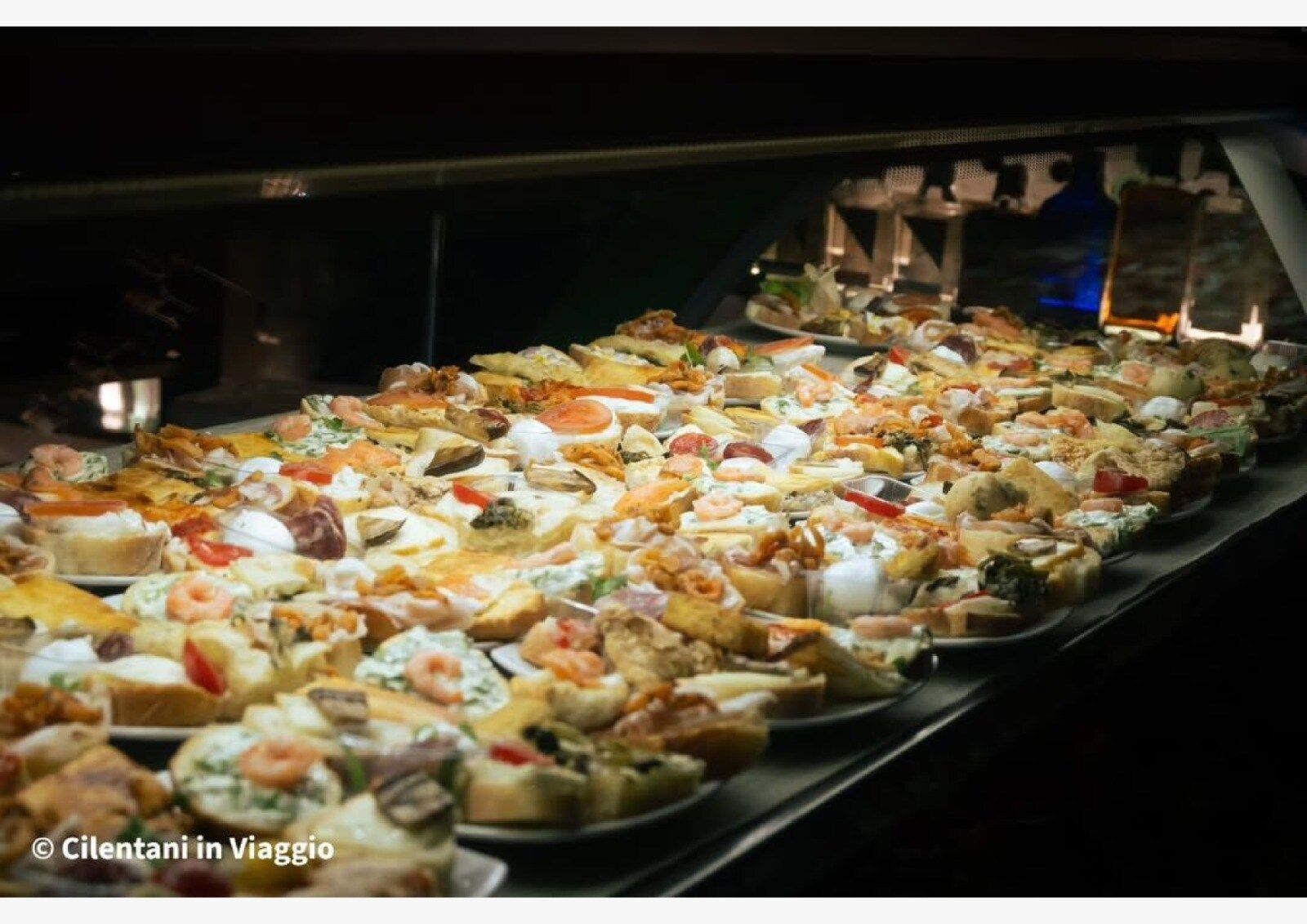 Una vetrina piena di una varietà di piccoli e colorati antipasti disposti su piatti, probabilmente per un ristorante.