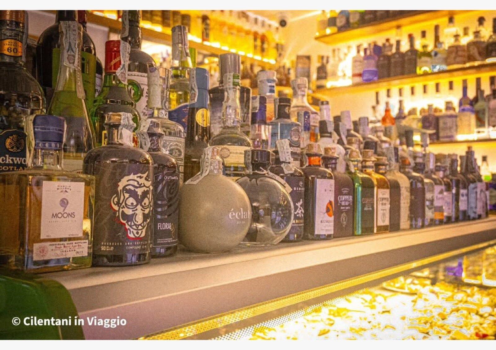 Bottiglie di liquore sullo scaffale di un bar, in un locale ben illuminato.