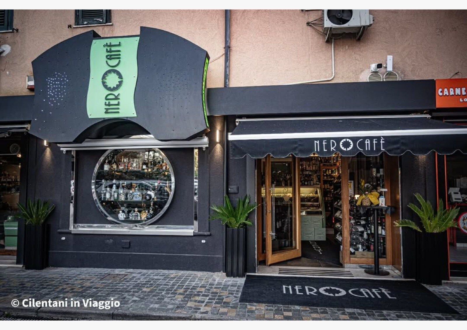 Ingresso del Nero Café con esterno nero, tenda da sole, finestra circolare e insegna sopra.