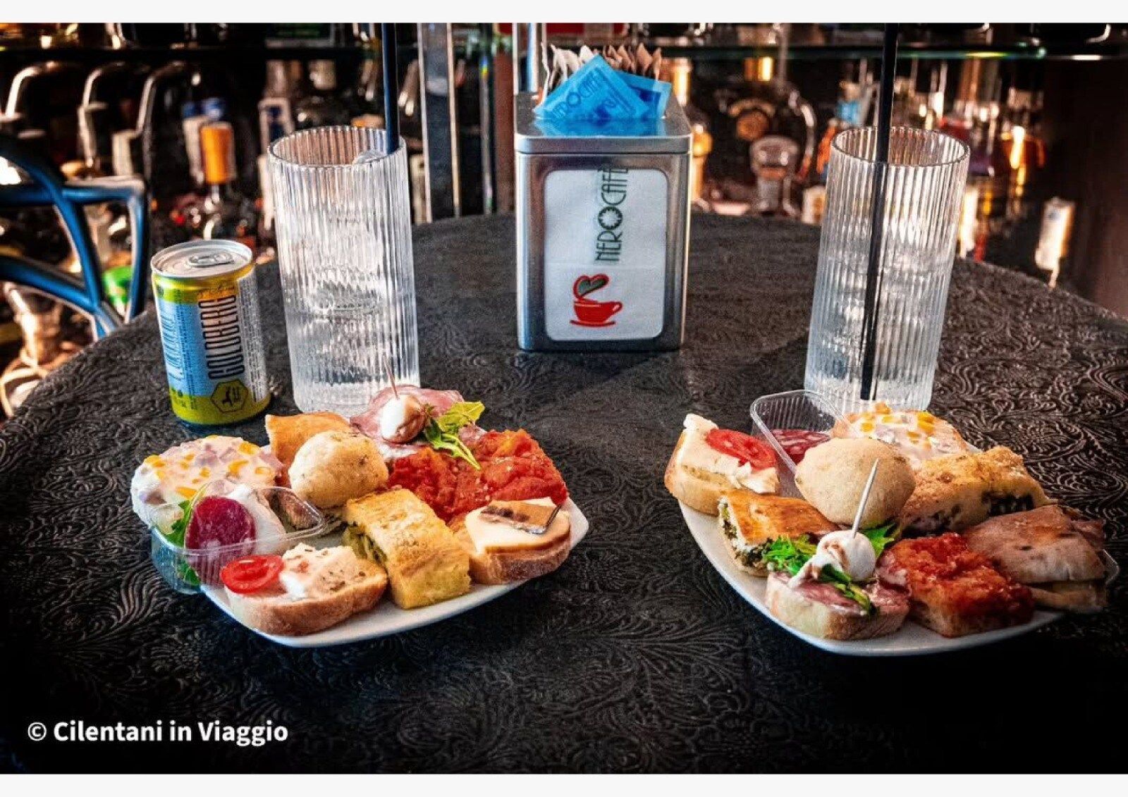 Due piatti di antipasti, bevande e un porta tovaglioli su un tavolo in un bar.