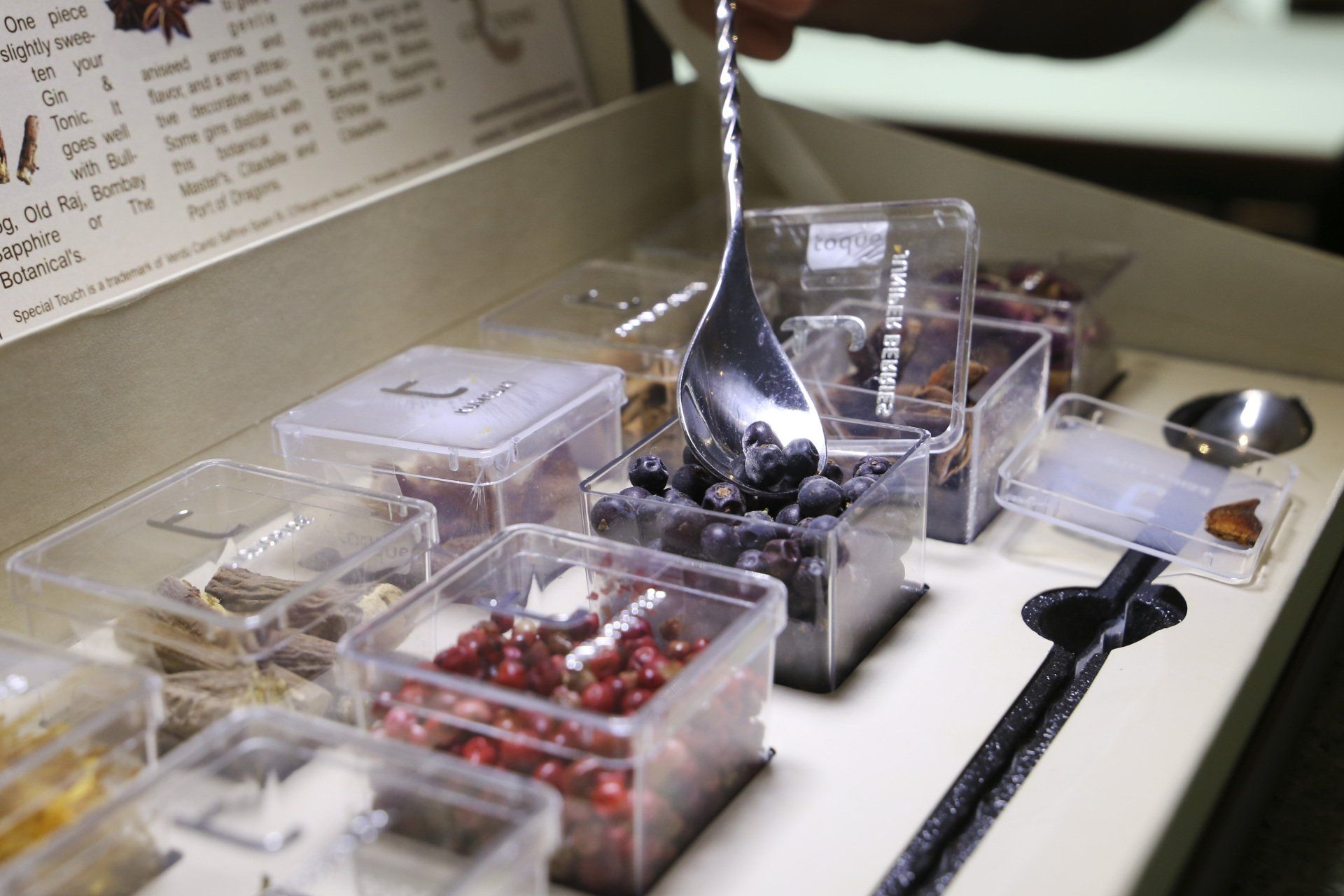 Persona che raccoglie more da un contenitore trasparente in un espositore per spezie.