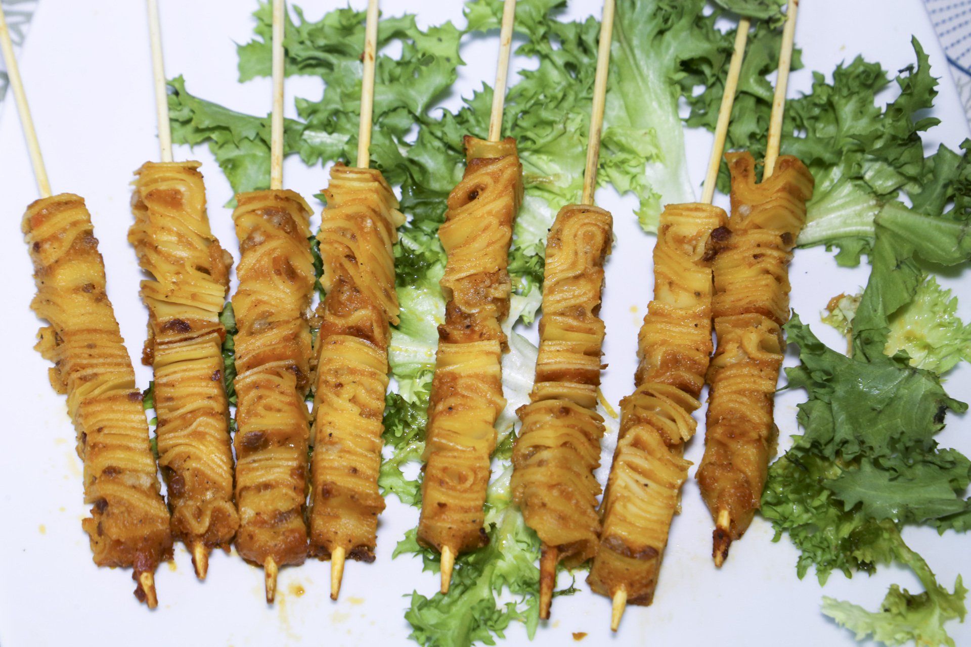 Involtini di cibo dorato, infilzati su un letto di lattuga verde, probabilmente pronti per essere serviti.