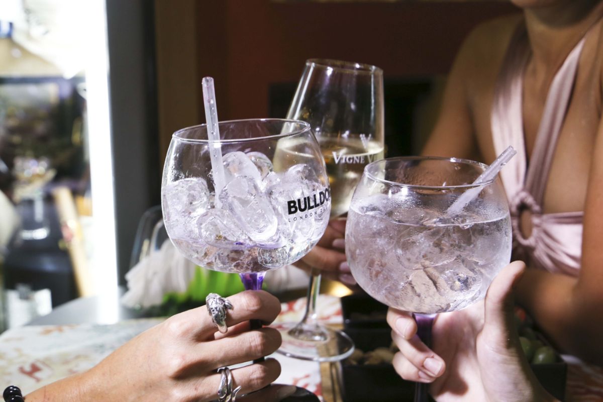 Tre persone brindano con bicchieri pieni di ghiaccio e bevande.