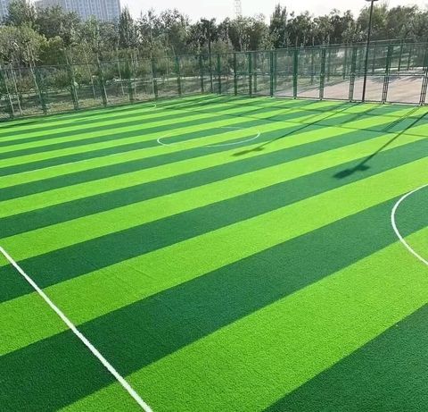 A sports field with light and dark green strips of artificial grass and and white lines.