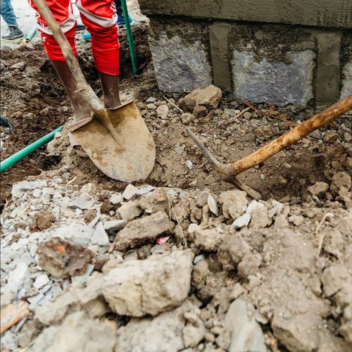 A person is digging in the dirt with a shovel.