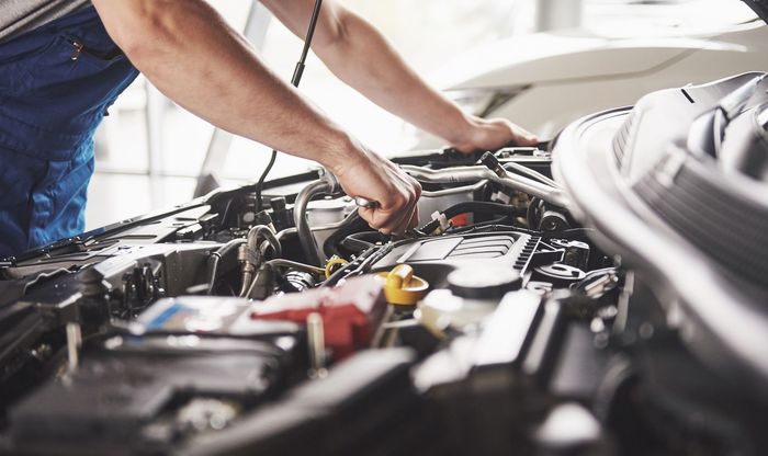 A man is working on the engine of a car.