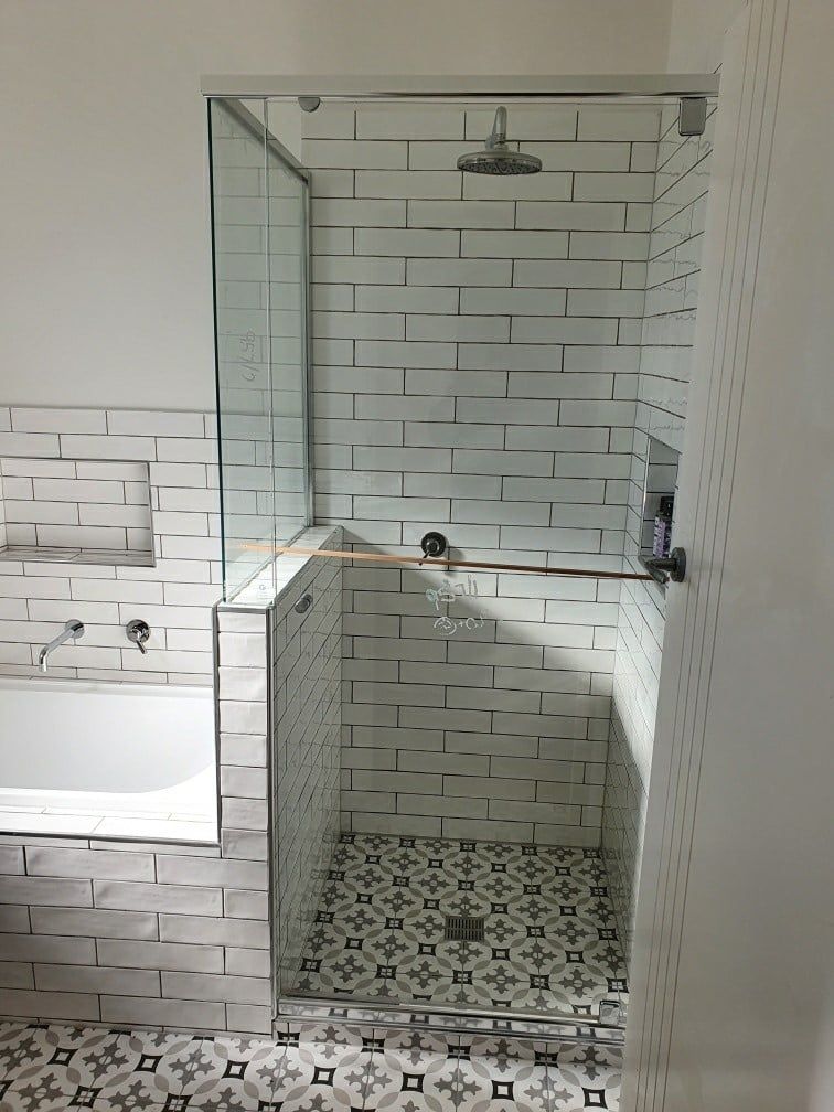 A bathroom with a shower screen, walk in shower and a bathtub.