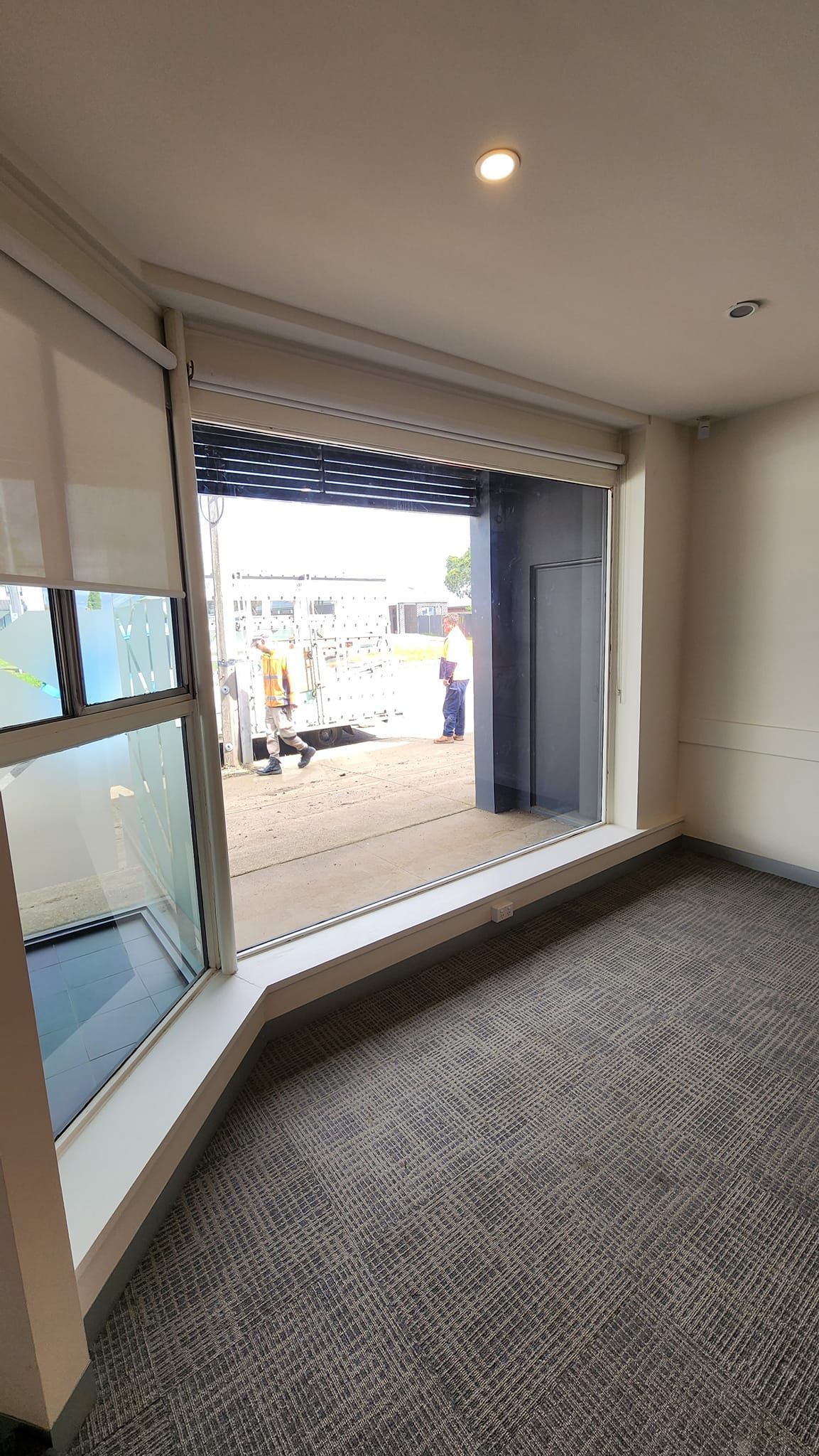 A room with a large window and a carpeted floor.