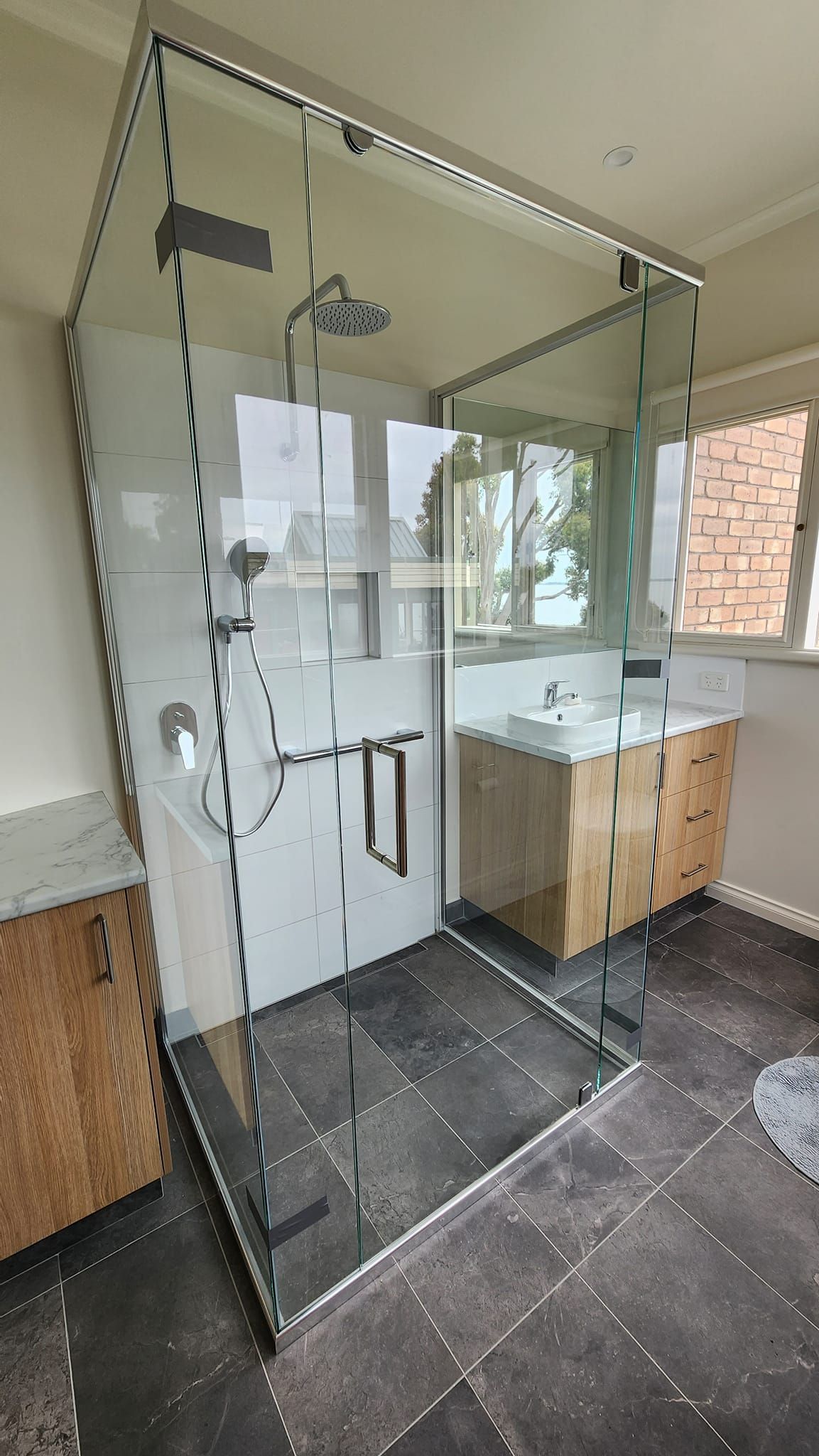 A bathroom with a walk in shower and a sink.