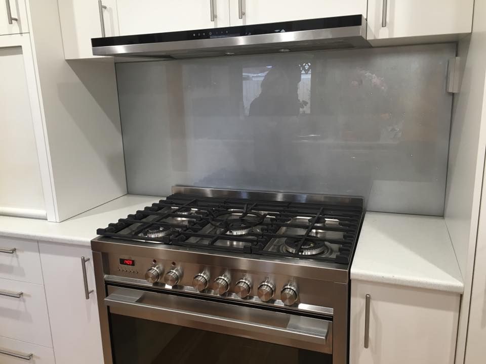 A stainless steel stove top oven is in a kitchen with white cabinets.