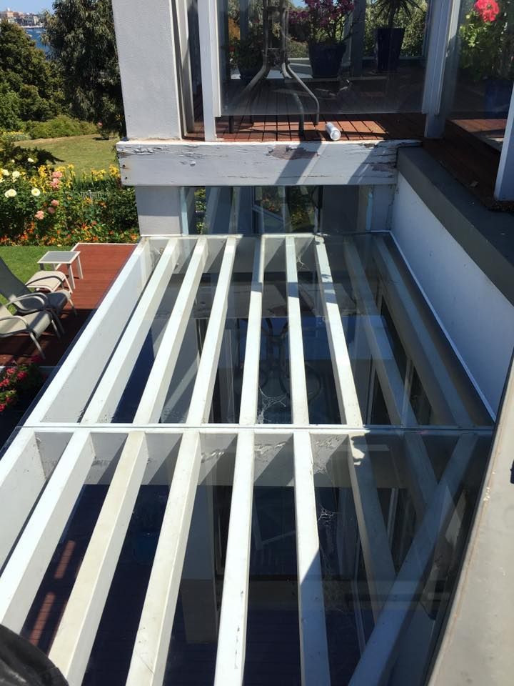 A white pergola with a glass roof is sitting on top of a building.