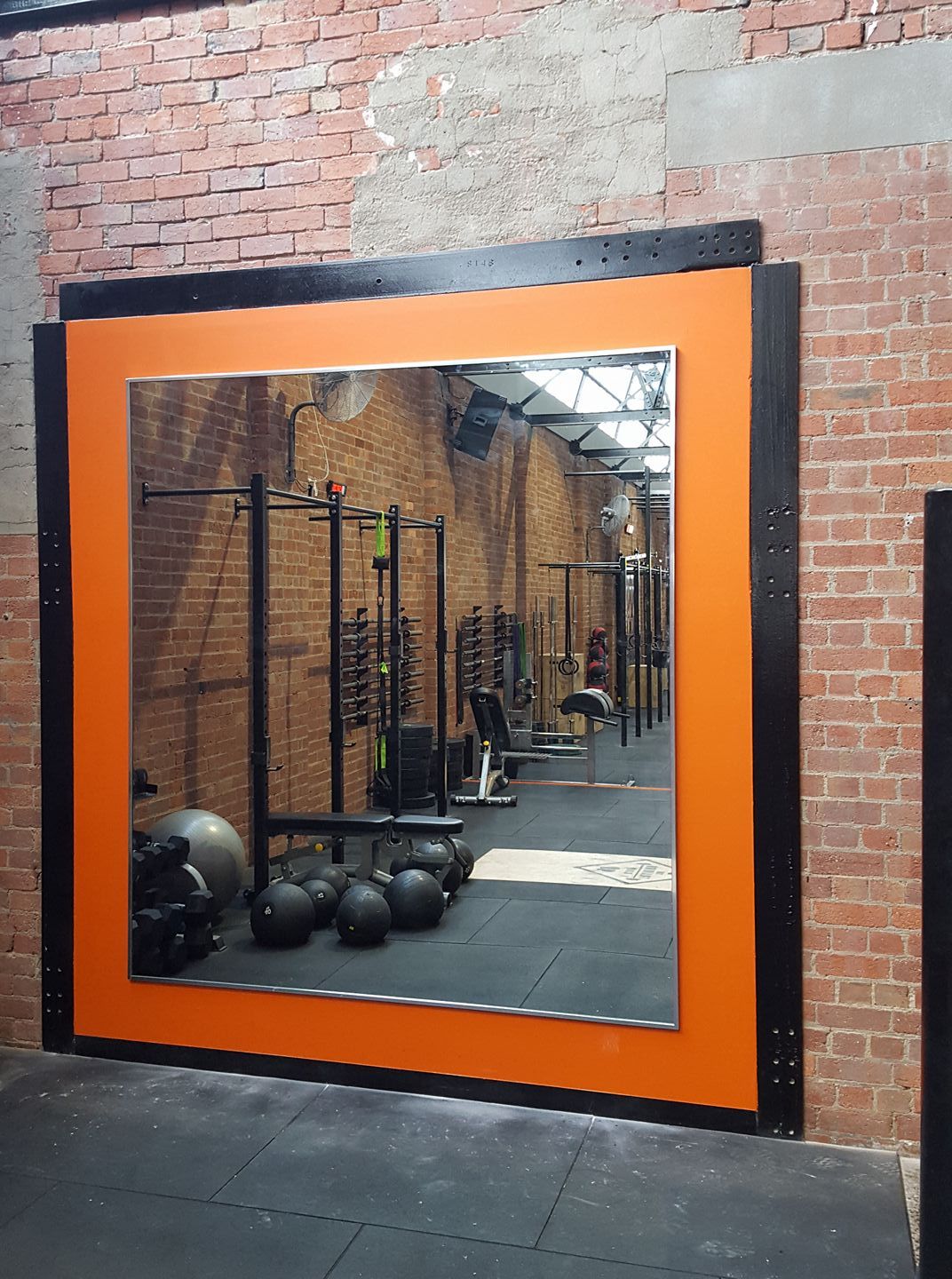 A large mirror in a gym with a brick wall