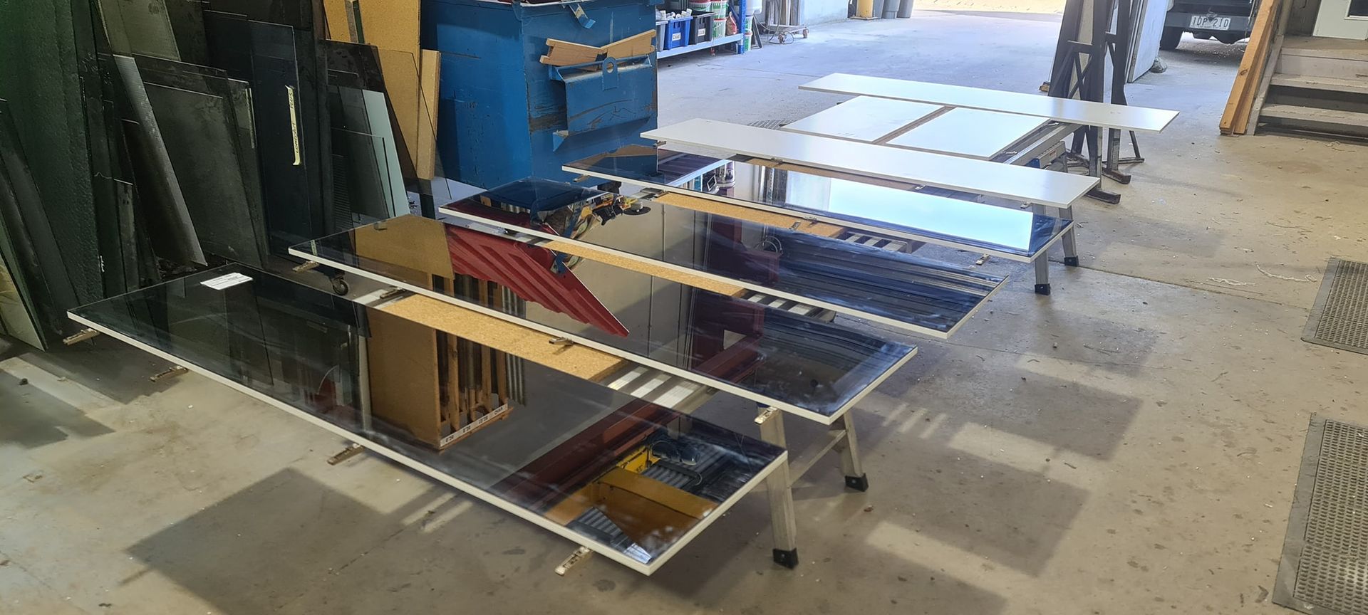 Mirrors and glass sheets on display in a workshop setting.